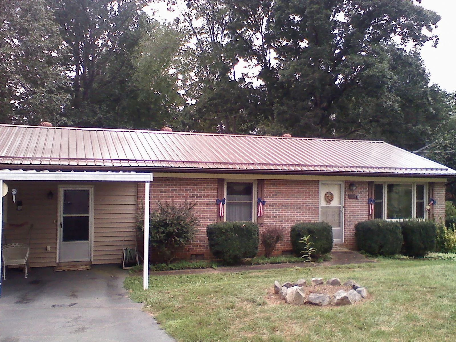 Bronze metal roof and carport on a brick ranch home — Roof Repair work by our crew in Saint Joseph