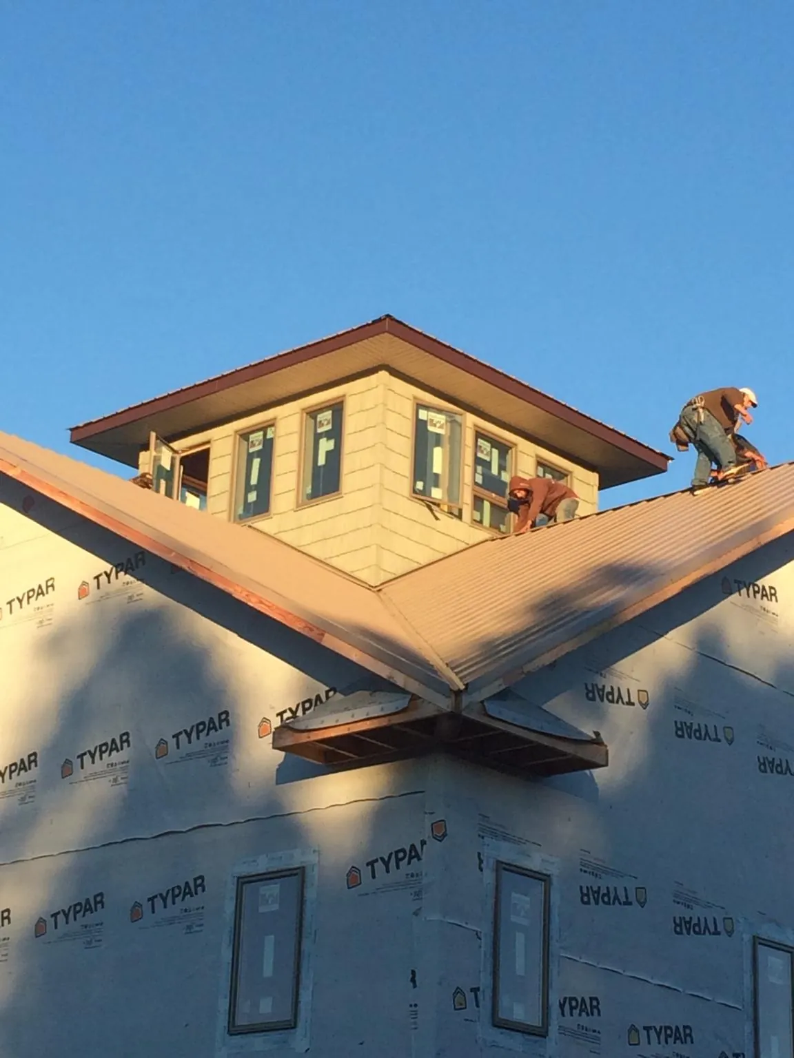 Roofers working around a rooftop cupola on a new metal roof at sunset — Roof Waterproofing in Saint Joseph by Roofing Brothers